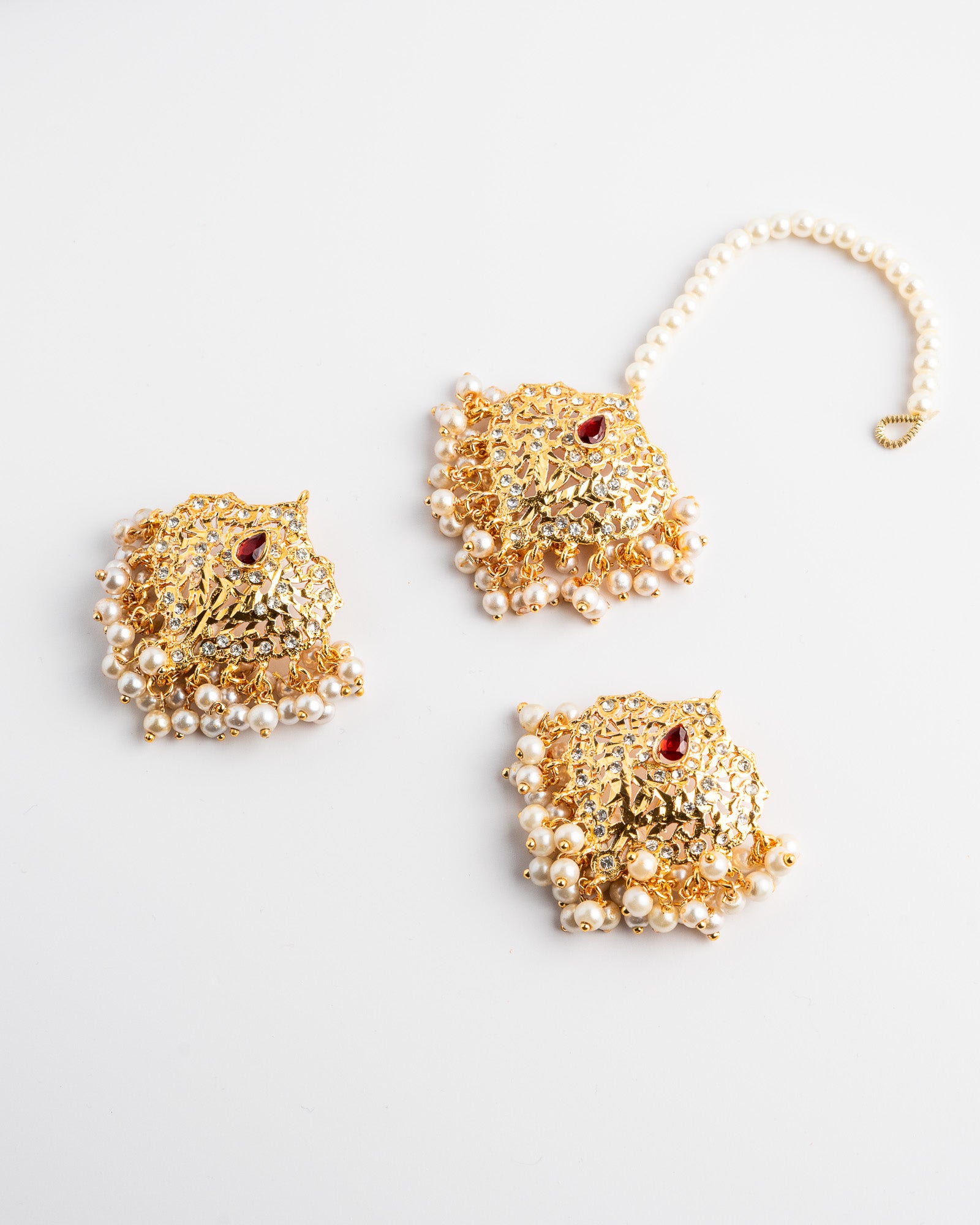 Golden and pearl earrings set on a white background