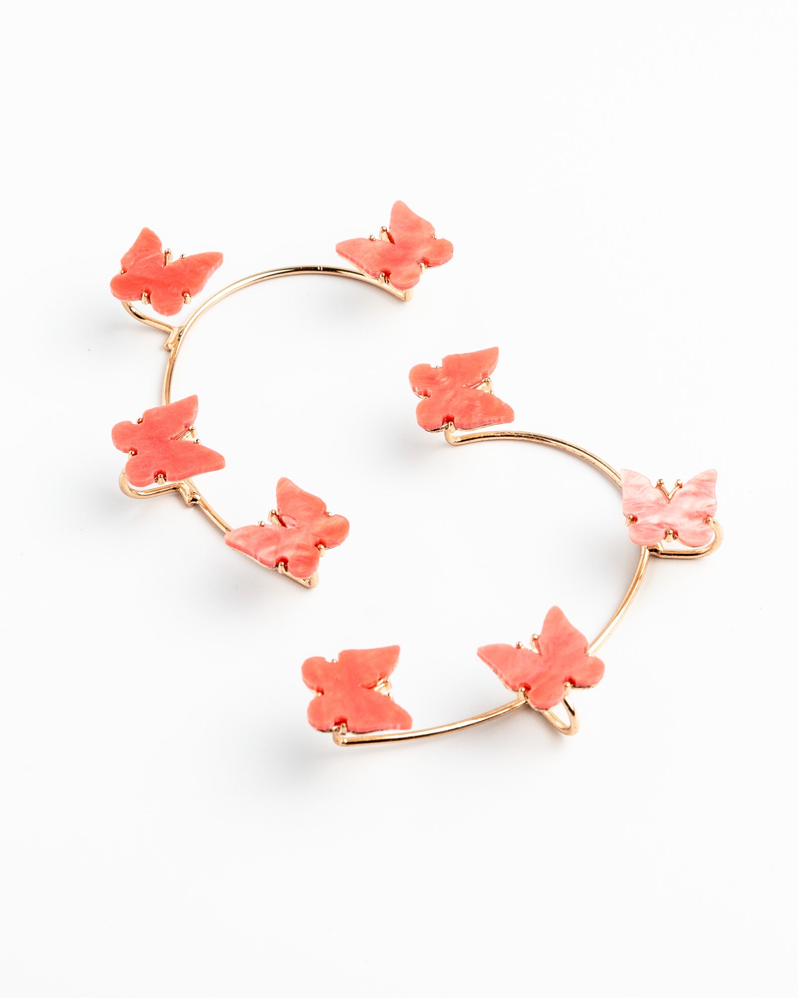 Heart-shaped earrings with salmon colored floral elements on a white background
