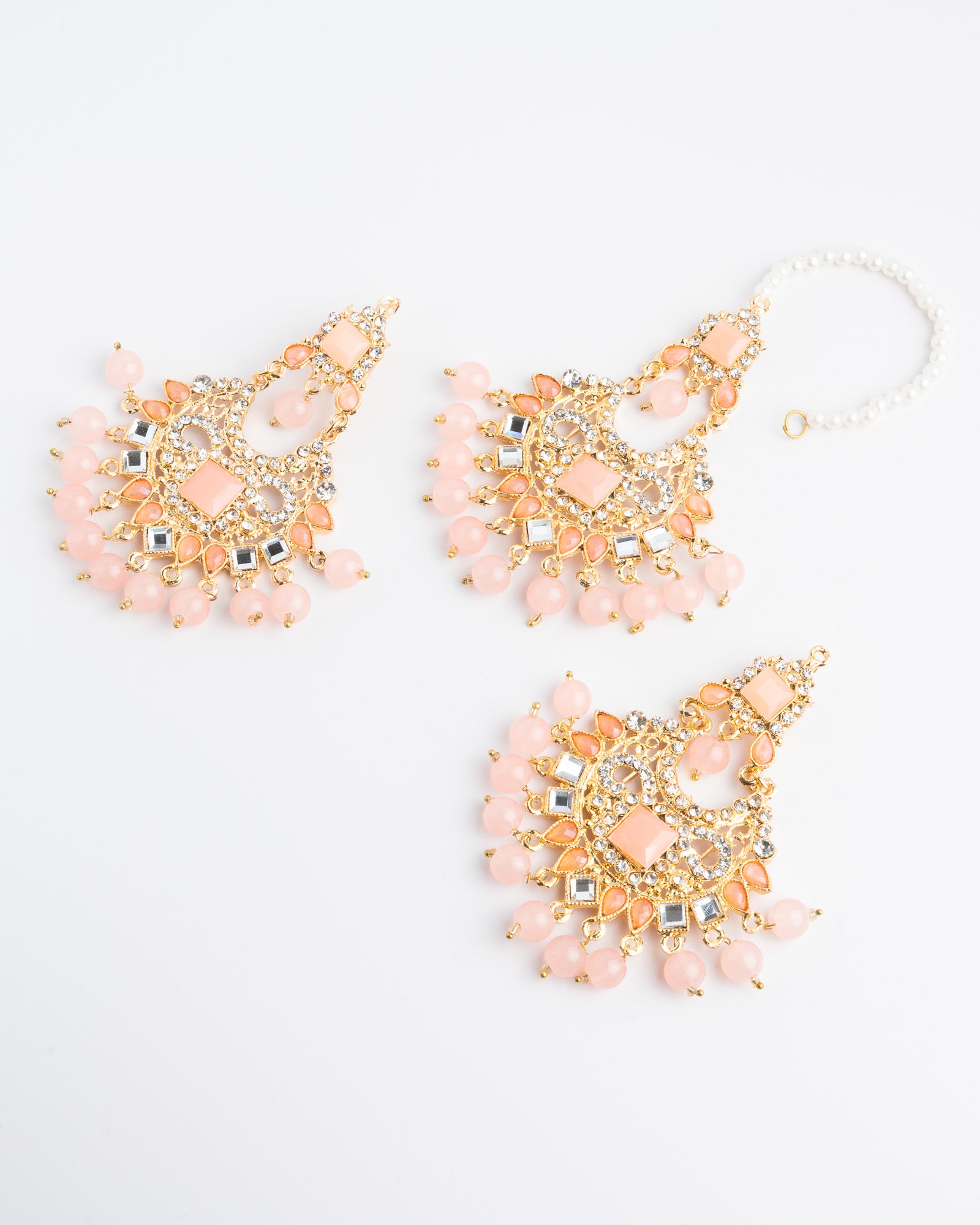 Peach colored beaded earrings set with gold accents on a white background