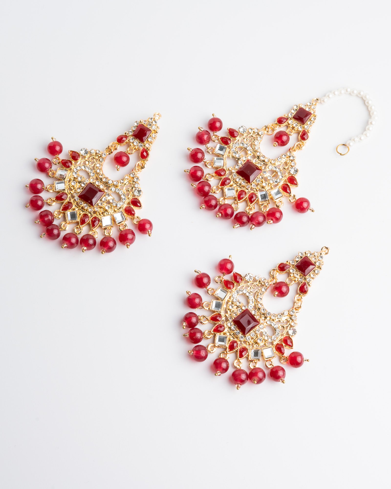 Red beaded earrings set with gold accents on a white background