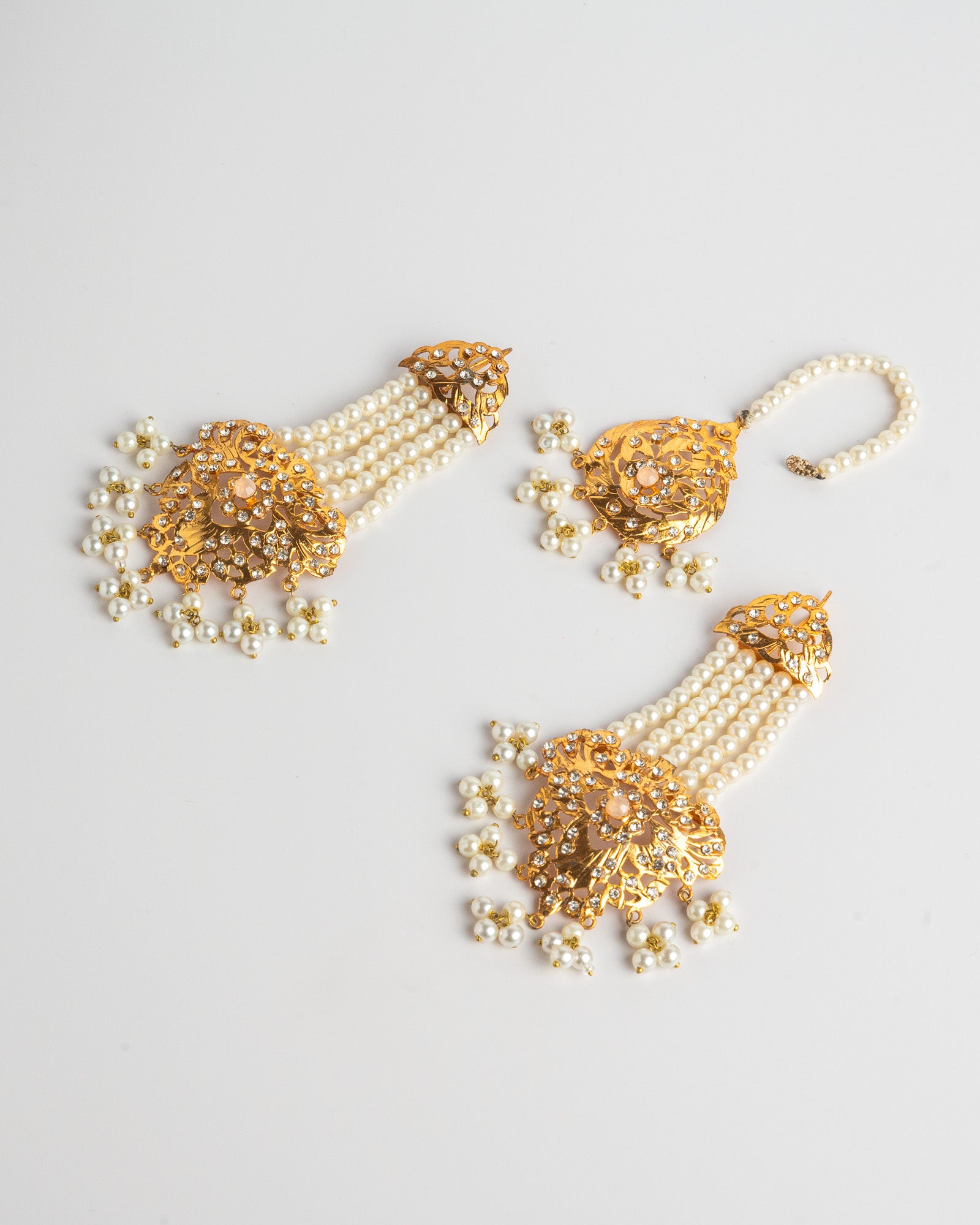 Golden and pearl earrings set on a light gray background