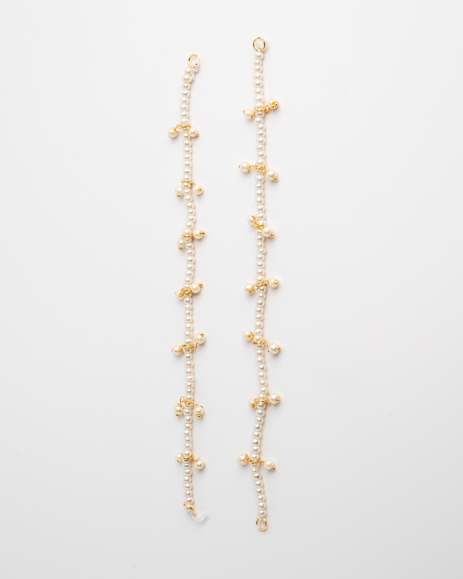 Pair of ear chain with luminous pearl beads. Spaced evenly along the chain are delicate clusters of tiny pearls