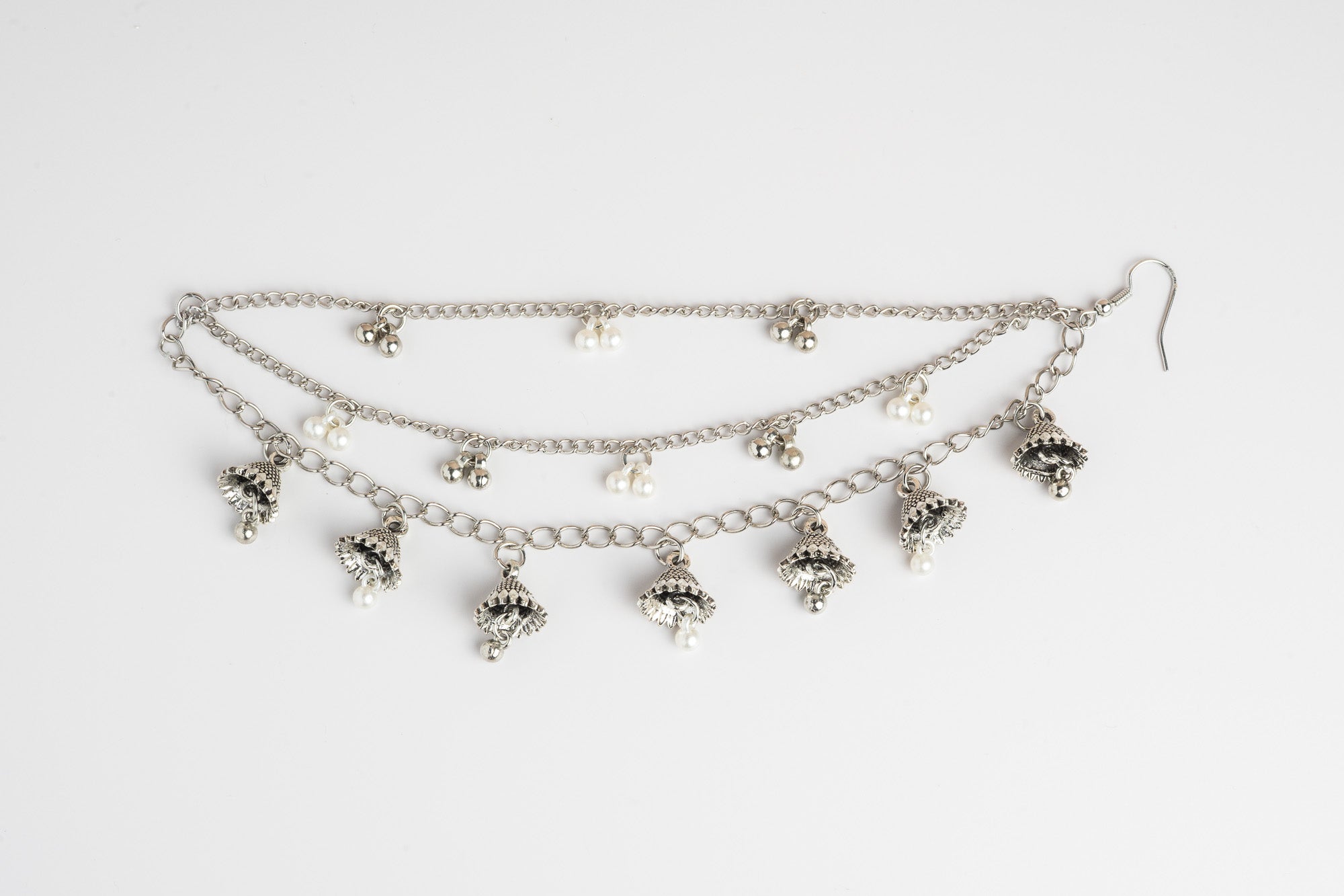 Silver ear chain with dangling charms on a white background