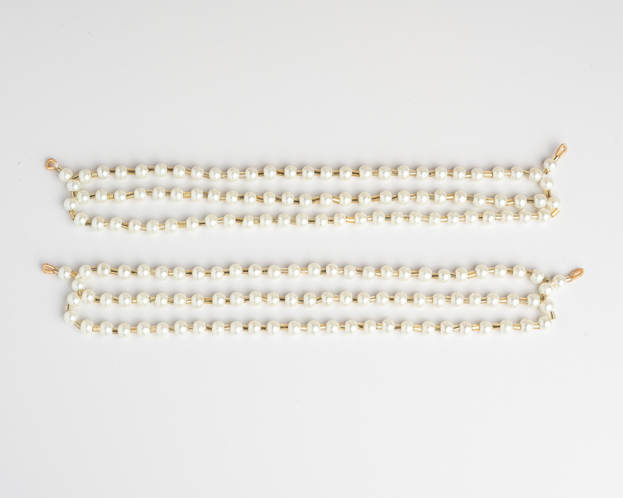 Pair of three layered pearl ear chain on a light gray background