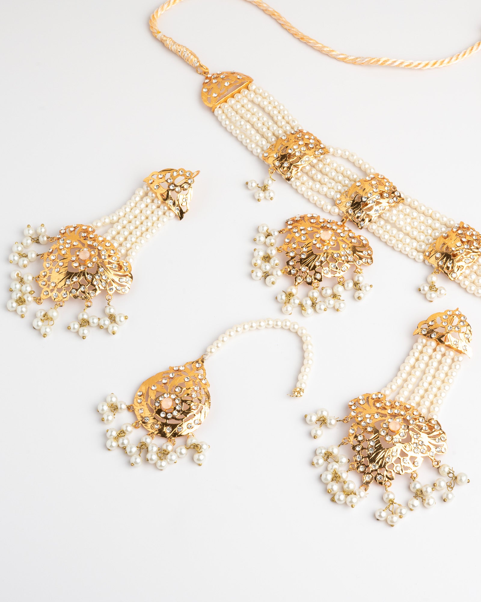Golden and pearl jewelry set on a white background
